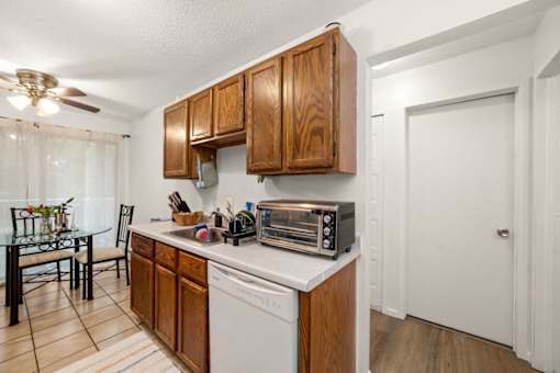 A kitchen with wooden cabinets and a white dishwasher.