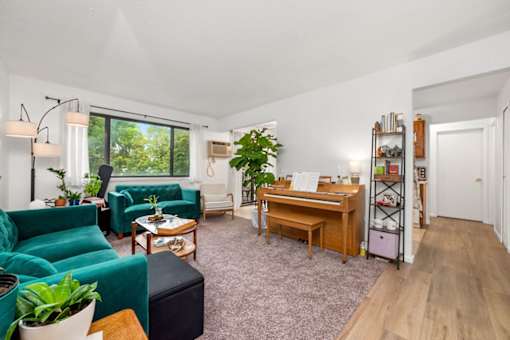 A living room with a green couch and a wooden desk.