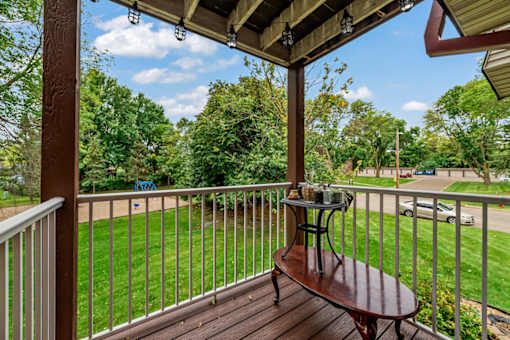 A wooden table is on a porch with a white railing.