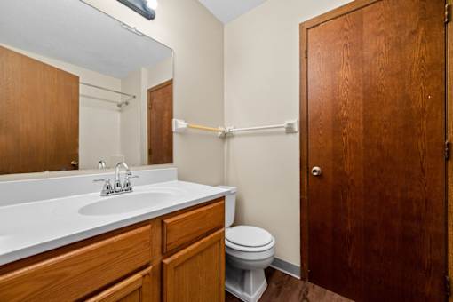 A bathroom with a toilet, sink, and wooden cabinetry.