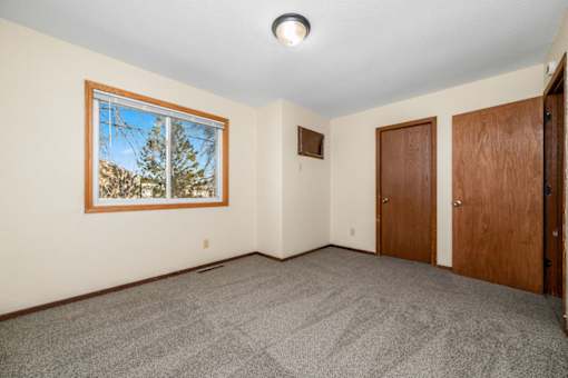 A room with a picture on the wall and two doors.