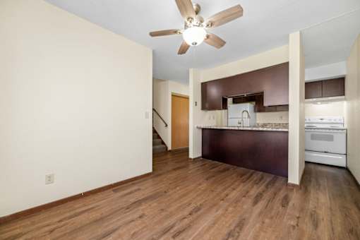 A room with a ceiling fan and wooden floors.