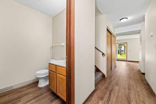 A white toilet sits in a small bathroom with wood floors and a wooden door.