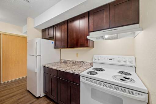 A kitchen with a white stove and refrigerator.
