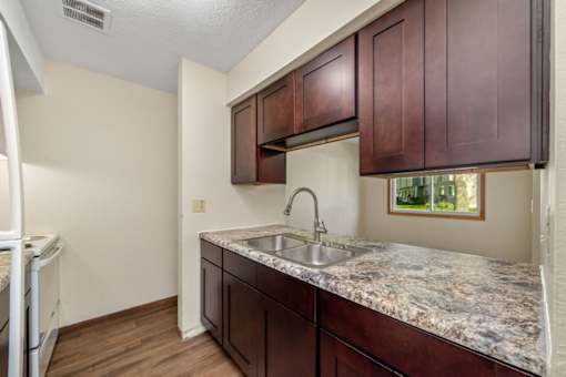 A kitchen with brown cabinets and a marble countertop.