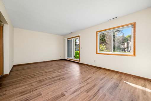 A room with wooden floors and a window showing a view of a house.