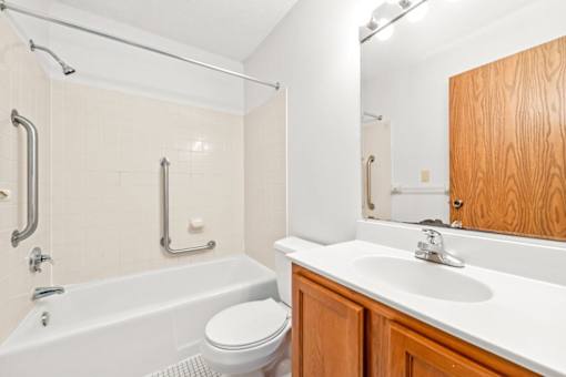 A white bathtub with a shower head and a white toilet in a bathroom.