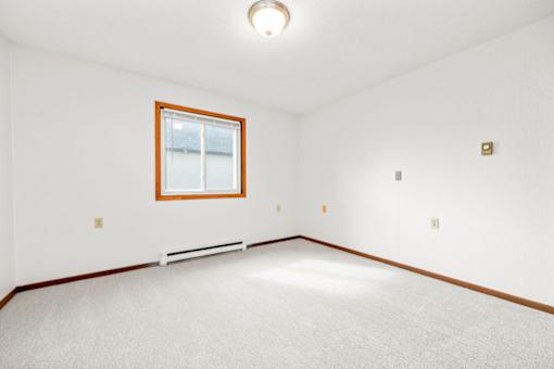 A white room with a window and a bench.