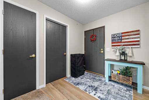A room with a black door, a grey door, and a black suitcase on the floor.