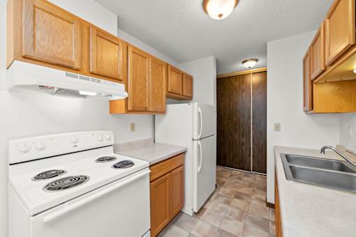 A kitchen with white appliances and wooden cabinets.