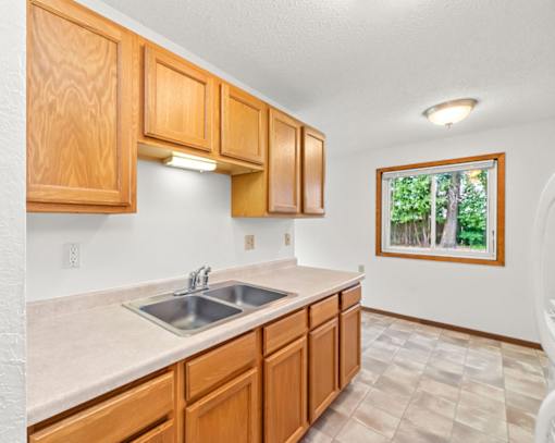 A kitchen with wooden cabinets and a window.