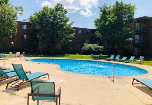 a swimming pool with chairs and a building in the background