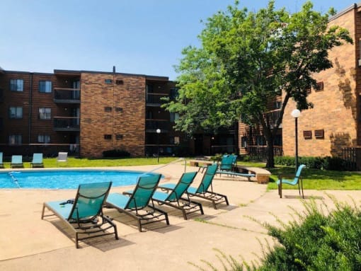 a swimming pool with blue chairs in front of a building