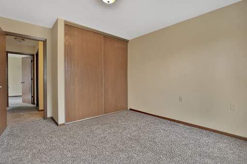 a bedroom with a closet and a carpeted floor