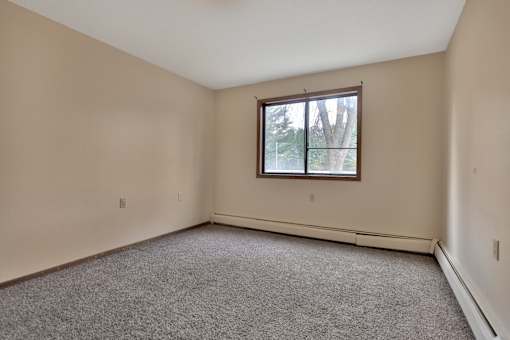 an empty living room with a window and carpet