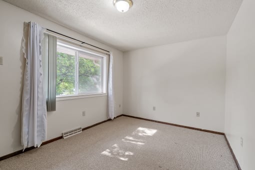 an empty room with a window and a curtain