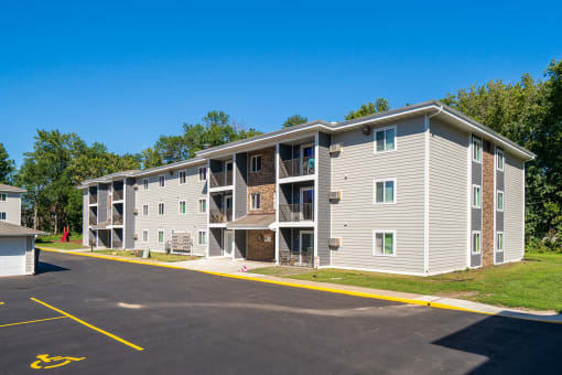an apartment building with gray siding and a parking lot