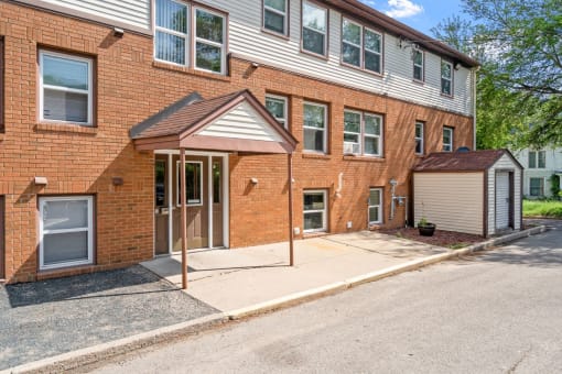 the front of a brick apartment building with a sidewalk and a driveway