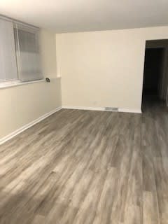an empty room with wooden floors and a window
