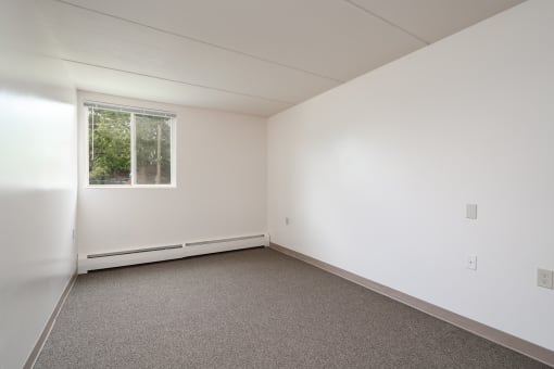 an empty room with white walls and a window
