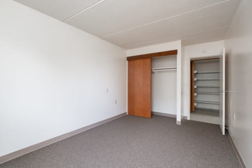 an empty room with white walls and a closet with a wooden door