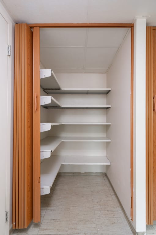 a walk in closet with white shelves and a door