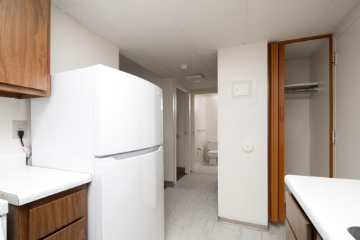 a kitchen with white appliances and a hallway to a bathroom