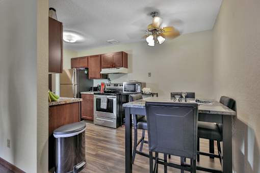 a kitchen with a bar and stools in front of a kitchen table with chairs
