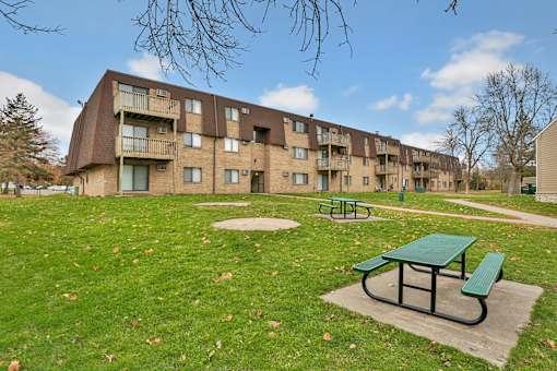 a green picnic table in a park in front of an apartment building
