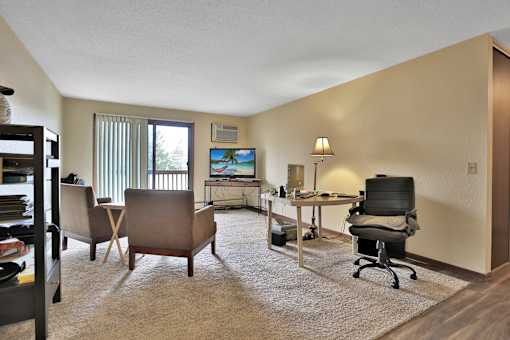 a living room with a desk and chairs and a tv