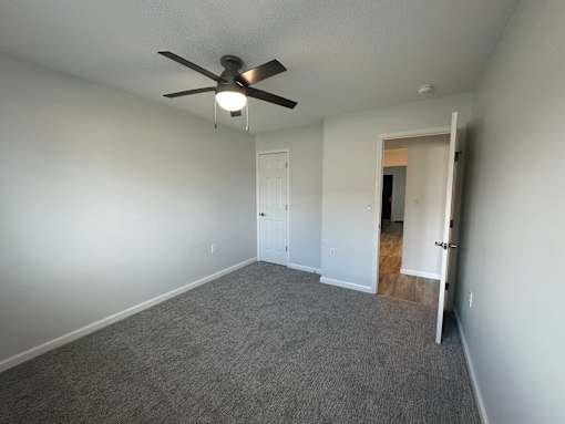 A room with a ceiling fan and carpeted floor.