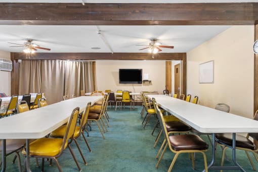a conference room with long tables and chairs and a tv