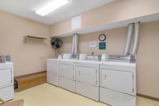 a laundry room with a row of washes and dryers in it