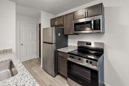 A kitchen with a stainless steel refrigerator, microwave, and oven.