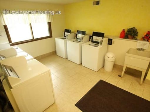 a laundry room with four washing machines and a window