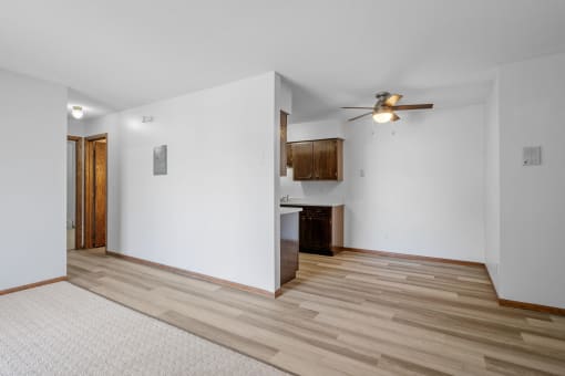 a living room with white walls and wood floors and a ceiling fan