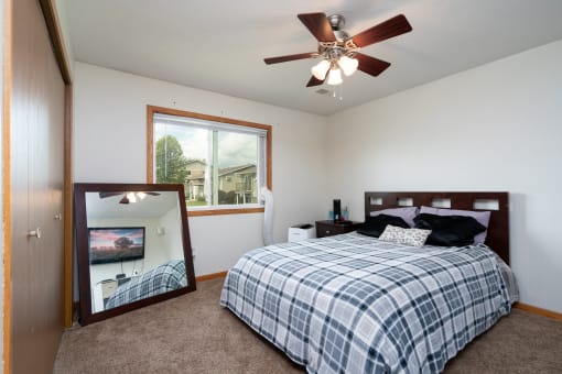 a bedroom with a bed and a mirror and a ceiling fan