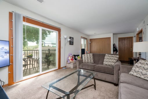 a living room with a couch and a glass coffee table and a sliding glass door