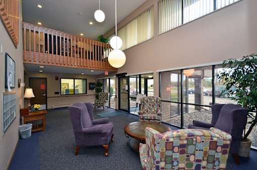 A living room with a purple chair and a multicolored ottoman.