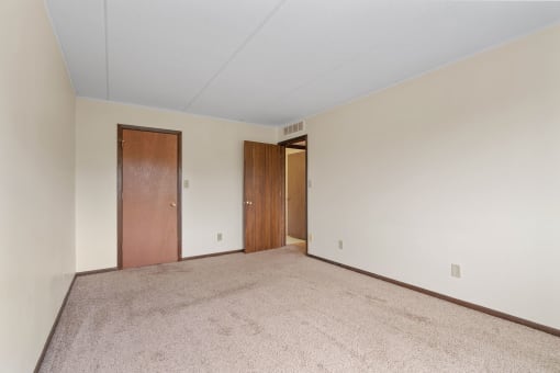 a spacious living room with carpet and a door to a hallway