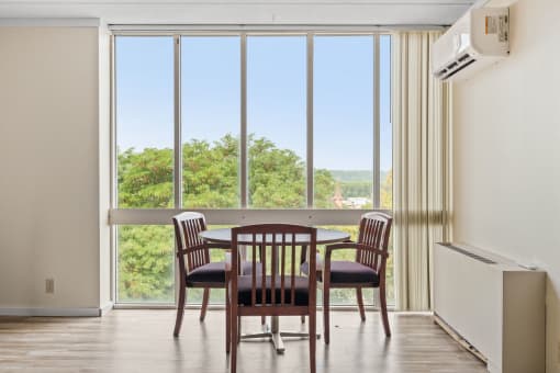 a dining room with a table and chairs in front of a window