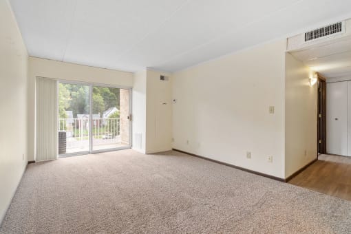 an empty living room with a sliding glass door to a patio