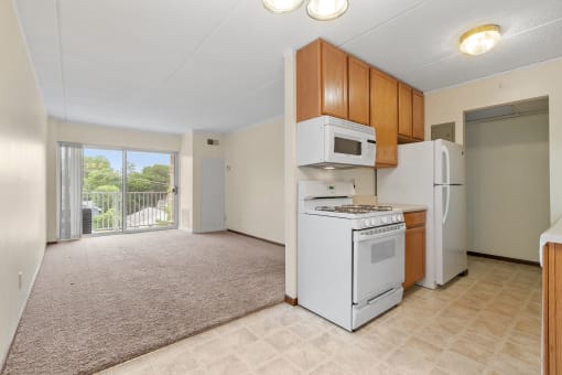 an empty kitchen with a stove refrigerator and microwave