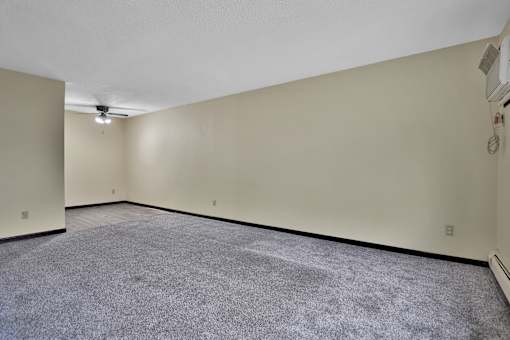 the living room of an empty house with carpet and a ceiling fan