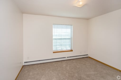 an empty room with a window and white walls