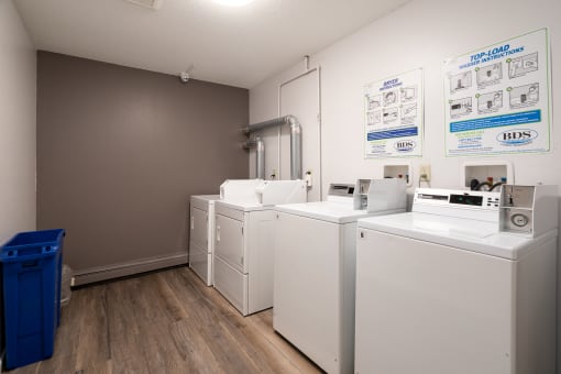 four washers and dryers in a laundry room with wood floors