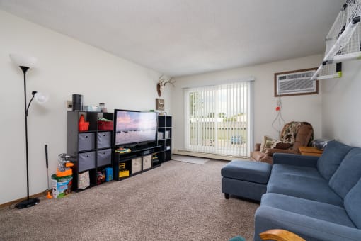 a living room with a blue couch and a tv on the wall