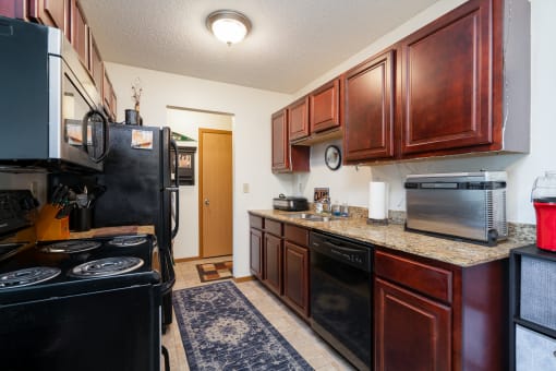 full kitchen with black appliances and granite counter tops and dark wood cabinets