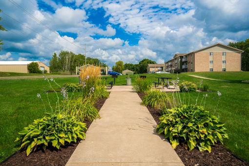 a sidewalk leading to a garden in front of a building