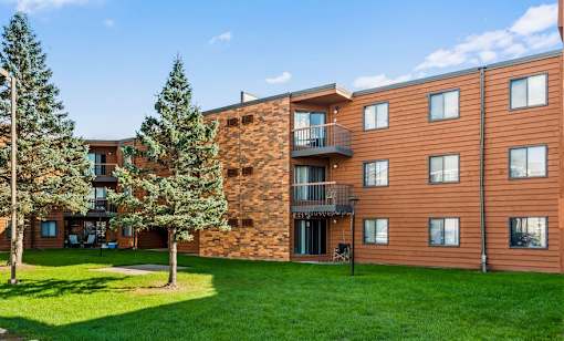 A large brown building with a balcony and a green lawn in front.